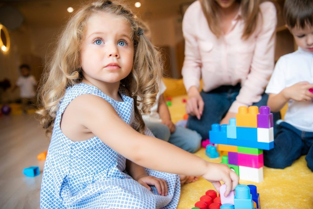 adorable kid playing with constructor and looking up in kindergarten